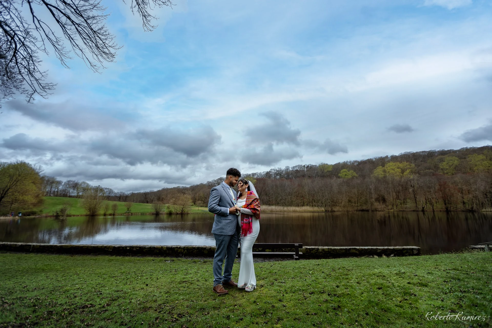 Pareja junto al lago bajo un cielo de nubes